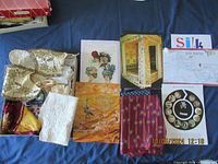 Overview of the silk exhibit contents showing silk fabric samples, educational displays, and printed materials arranged in a box.