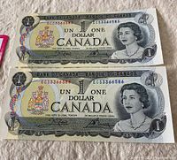 Two 1973 Canadian one dollar bills with consecutive serial numbers ECS3366585 and ECS3366586, uncirculated condition.