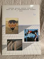 White soft cover booklet with grid design and images of hot air balloon, athlete, and bridge.