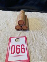 Three rolls of 1975 Canadian 1 cent coins stacked in a pyramid shape wrapped in original brown paper.