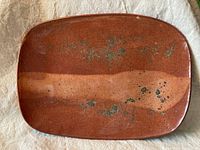 Top view of rectangular reddish-brown glazed clay serving dish showing speckled finish and smooth but textured surface.