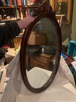 Full view of the wooden oval mirror showing the frame and reflective glass surface
