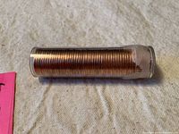 Side view of clear plastic roll containing stacked copper-colored Canadian pennies.