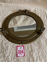 Full view of circular brass marine porthole mirror with round reflective glass and rivet details around frame.