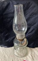 Full view of the tall clear glass oil lamp showing the chimney, burner, and base.
