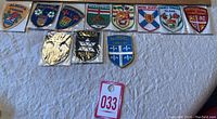 Front view of all emblems laid out on a white surface showing colorful patches and metal badges from Canadian provinces.