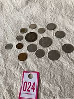 Group shot of 14 world coins on white cloth, varying sizes and metals
