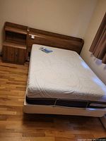 Full room view showing mattress on adjustable base, headboard and nightstand