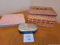 Photo of the three containers: rectangular woven antique sewing basket with a handle, a blue box, and an octagonal button tin on a wooden surface.