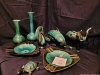 Eight Blue Mountain Pottery items displayed on fabric backdrop: two vases, horn planter, whale, elephant, turtle figurines, and two ashtrays.