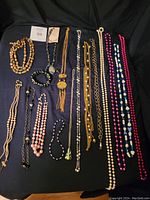 Overview of assorted vintage and modern costume jewelry, includes necklaces and bracelets in various colors and styles.