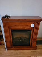Front view of Dimplex electric fireplace with wooden mantle and visible ruler showing height