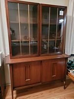 Full front view of the two-piece wooden china cabinet hutch with glass upper doors and wooden lower section.