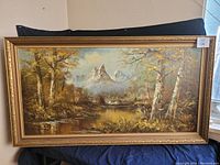 Frontal view of the signed landscape painting in ornate gilded frame