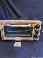 Front view of KitchenAid stainless steel toaster oven with visible control knobs and glass door.