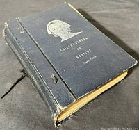 Angled view of the closed, dark blue textured nursing textbook with silver embossed image of a nurse on the cover, showing some wear along edges and corners.