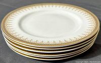 Stack of six white bone china dessert plates with gold and black ornate 'Athena' pattern borders.
