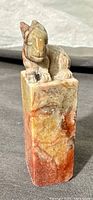 Front view showing carved rabbit figure atop rectangular variegated soapstone base with multi-color tones.
