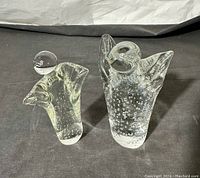 Two clear glass angel sculptures side by side on dark fabric background, showcasing their size and bubble details.