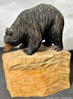 Angle view showing the carved black bear standing on textured wooden base.