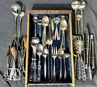 Wide shot of the wooden drawer filled with assorted vintage EPNS flatware and serving pieces including spoons, forks, ladles, and tongs, arranged on blue felt.