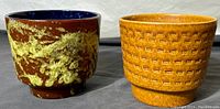 Two vintage W. German pottery planters side by side, showing their distinct colors and textures.