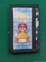 Front of the tri-fold wallet showing a hologram of Mario holding a yellow mushroom against a brick wall with a sun in the background.