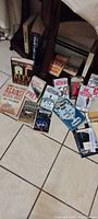 Photo of 17 assorted books laid out on tiled floor including books by James Patterson, Alex Cross series, Stephen King and others.