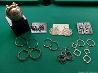 Overview of lot showing multiple pairs of earrings and a decorative trinket container.