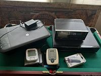 Full lot overview showing printer, vintage TV/VCR unit, VHS player, blood pressure monitors, and handheld massager