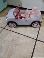 Side view of Lori Dolls toy convertible car showing pink seats and white body.