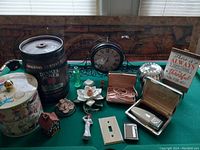 Wide view of lot items showing the clock, shavers in boxes, ceramic figurines, beer can, and miscellaneous small household items
