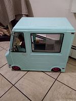 Side view of the light blue plastic ice cream truck toy with pink wheels and visible interior.