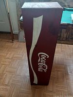 Side view showing Coca-Cola logo on wooden shelf