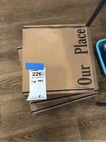 Three cardboard boxes labeled 'Our Place' containing dishware sets.