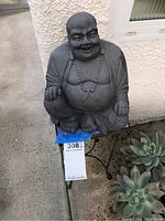 Front view of the Buddha garden sculpture sitting on the metal plant stand showing the full figure and facial detail.