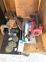 Overview photo showing Milwaukee circular saw and metal C-clamp inside a wooden box with a tag numbered 260