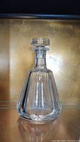 Full view of Baccarat crystal decanter with stopper against gold background showing overall shape and clarity.