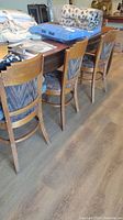 Side view showing three of the wooden dining chairs with upholstered seats and backs, lined up beside a wooden table
