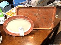 Oval platter and rectangular tray displayed on a wooden surface, showing marbled reddish-brown rims.