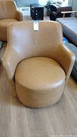 Front view of caramel faux leather swivel bucket chair showing rounded seat and arms, and smooth upholstery.