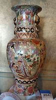 Front view of ceramic Chinese vase showing detailed hand-painted figures and floral pattern with metal ring handles on neck.
