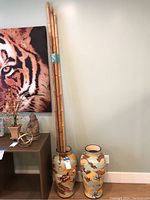 Two tall ceramic vases with dragon and yin-yang designs, one vase filled with five long bamboo sticks, displayed on floor near wall outlet.