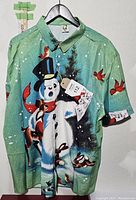 Front side of new XXL Hawaiian shirt with Christmas retro print featuring snowman, deer, rabbits, and red birds on green background.