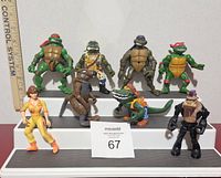 Eight Teenage Mutant Ninja Turtles and related character action figures displayed on a white stepped riser with ruler visible for scale.