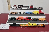 Top down and front view of 17 miniature die-cast cars and trucks on three tiers, showing various makes, models, and colors