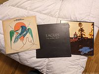 Three Eagles LP record albums laid out, front covers showing: Hotel California, The Long Run, and One of These Nights.