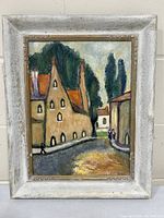 Front view of the framed oil painting showing the abstract town scene with buildings, street, people, and trees.