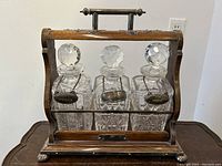 Front view of oak tantalus stand holding three cut crystal decanters