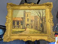 Oil painting with ornate gold frame showing an English historic building and a figure, signed by Marion Hannah.